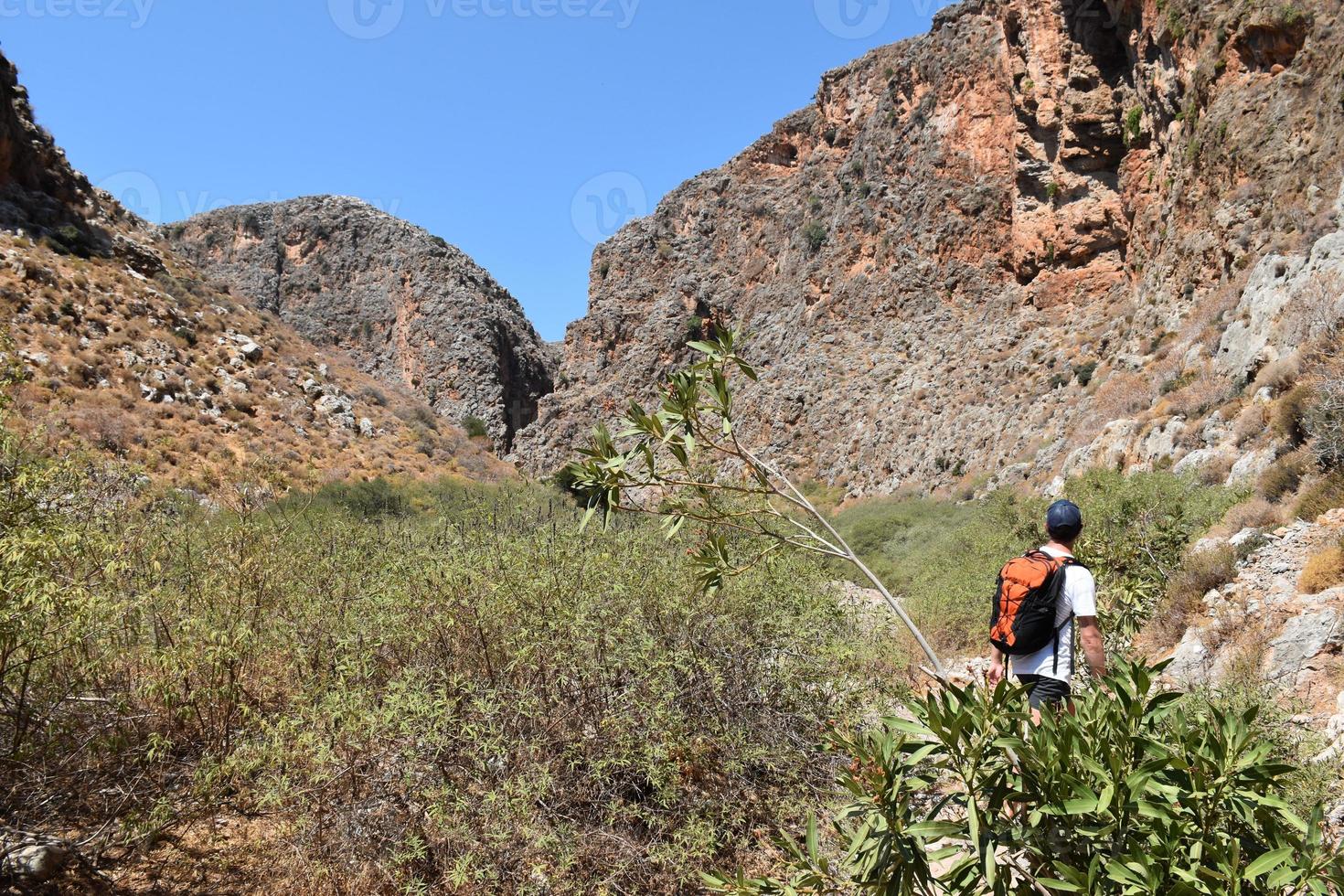 Man with backpack hiking among the vegetation in mountain valleys photo
