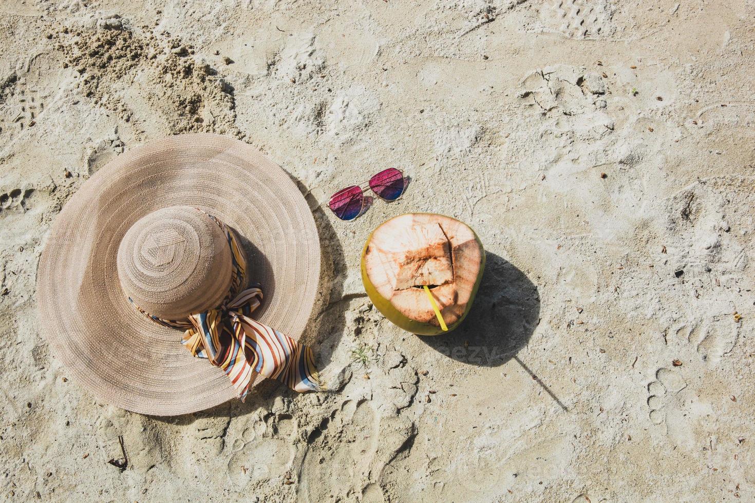 Top view of summer hat and sunglasses with coconut fruit isolated on beach sand background photo