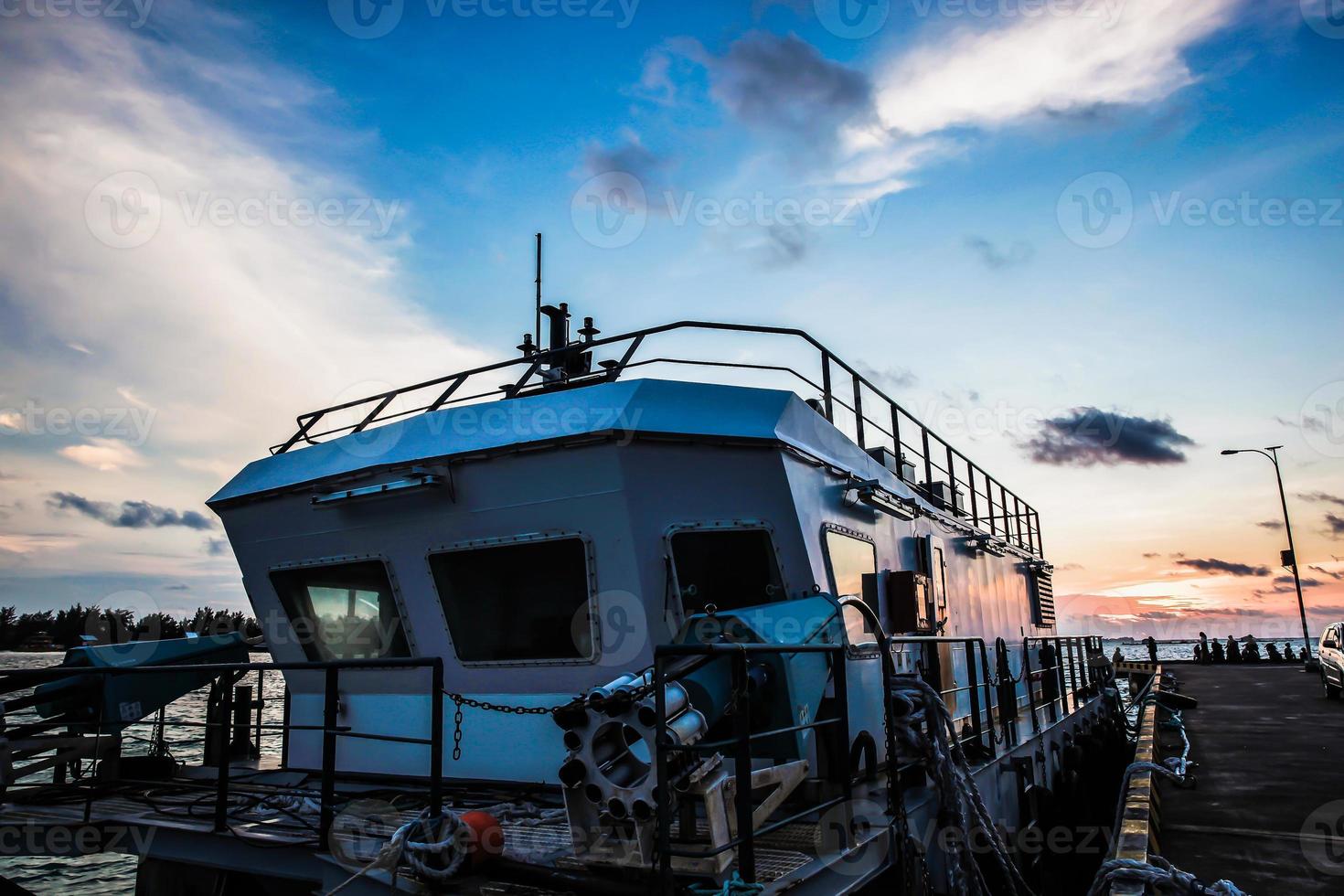 A ship floating in a harbor with beautiful sky background during sunset at Karimun Jawa Island photo