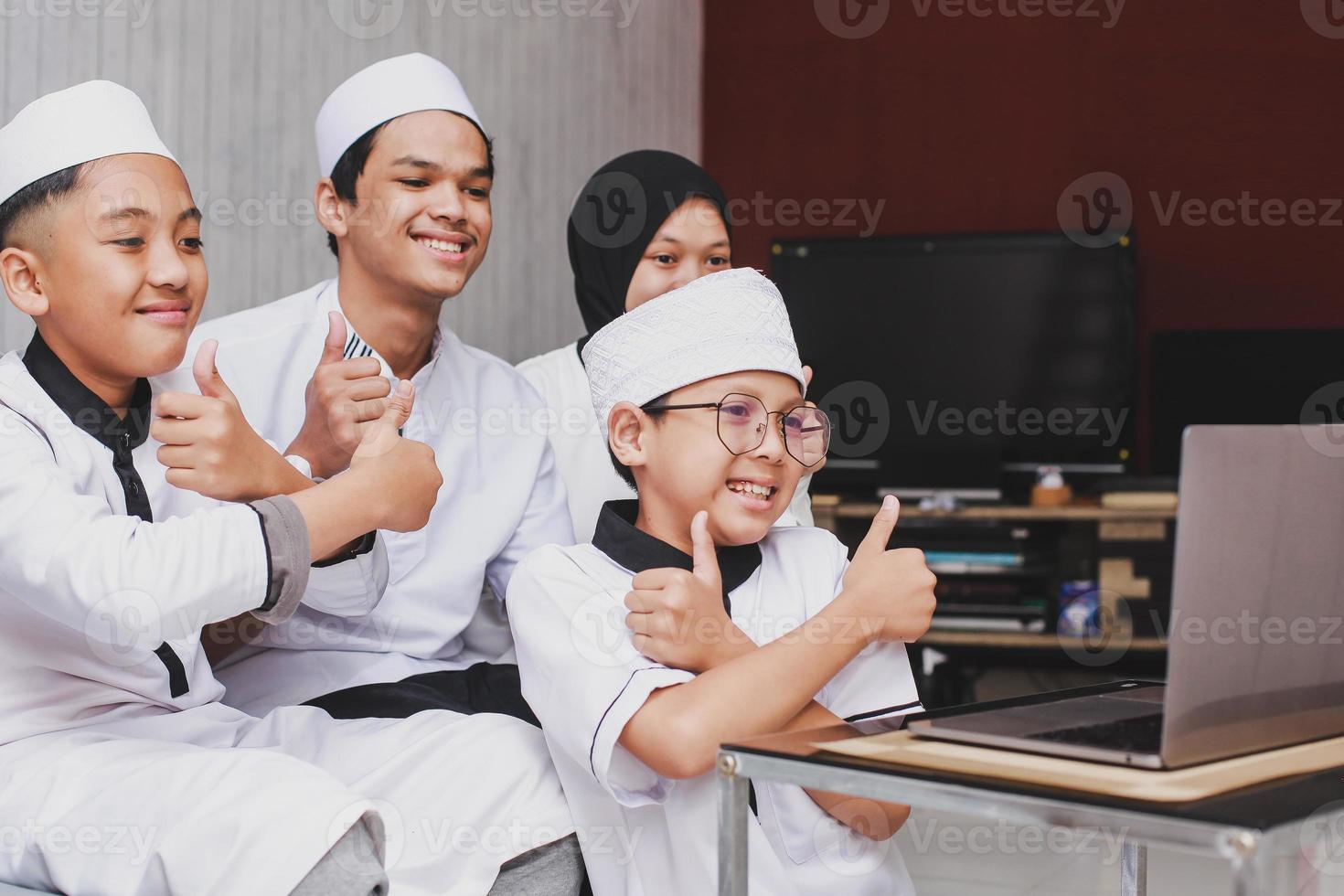 feliz familia musulmana haciendo una conversación en video y divirtiéndose frente a una laptop con gesto de pulgar hacia arriba durante la celebración de eid mubarak foto