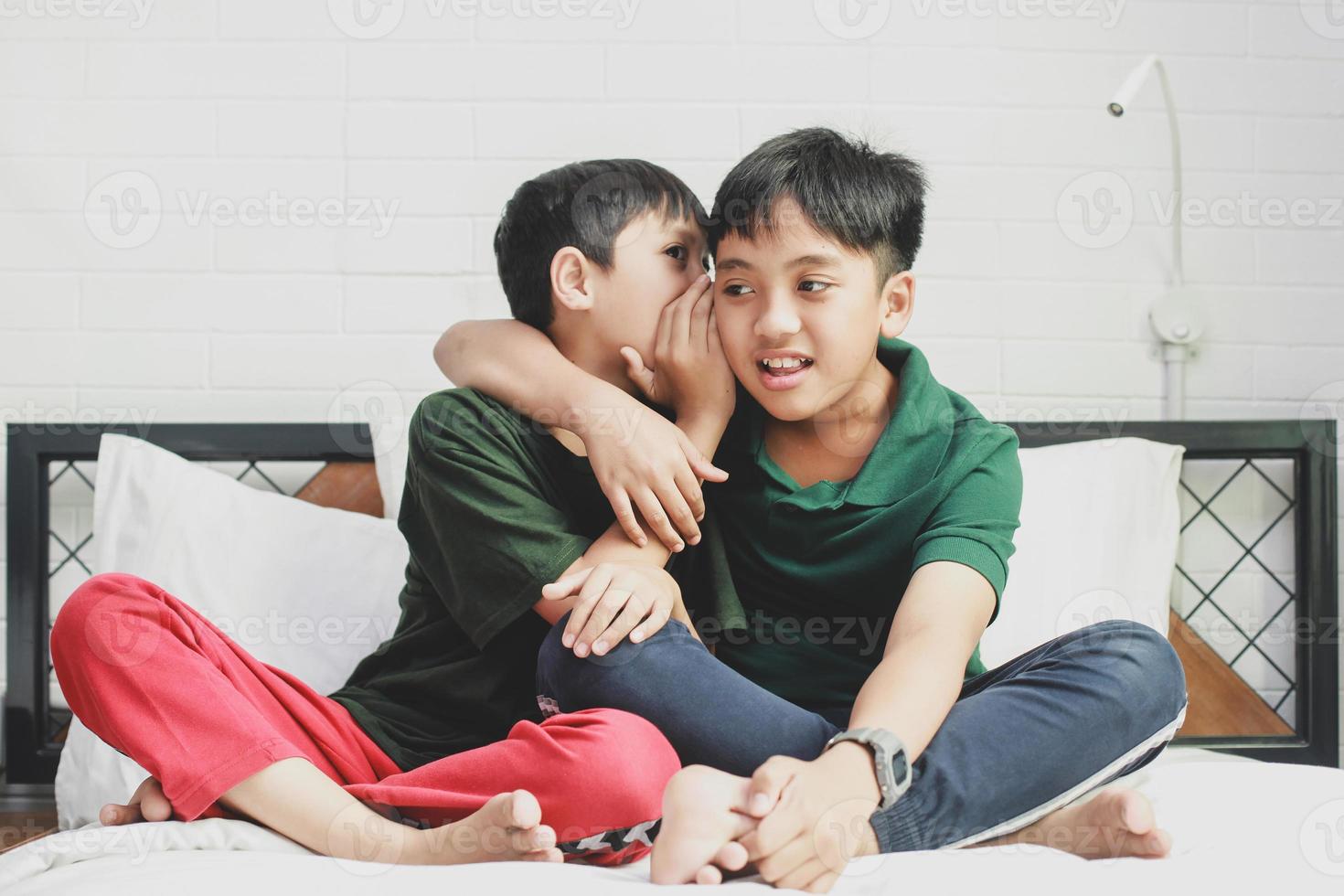 A boy whispered to his brother on the bed photo