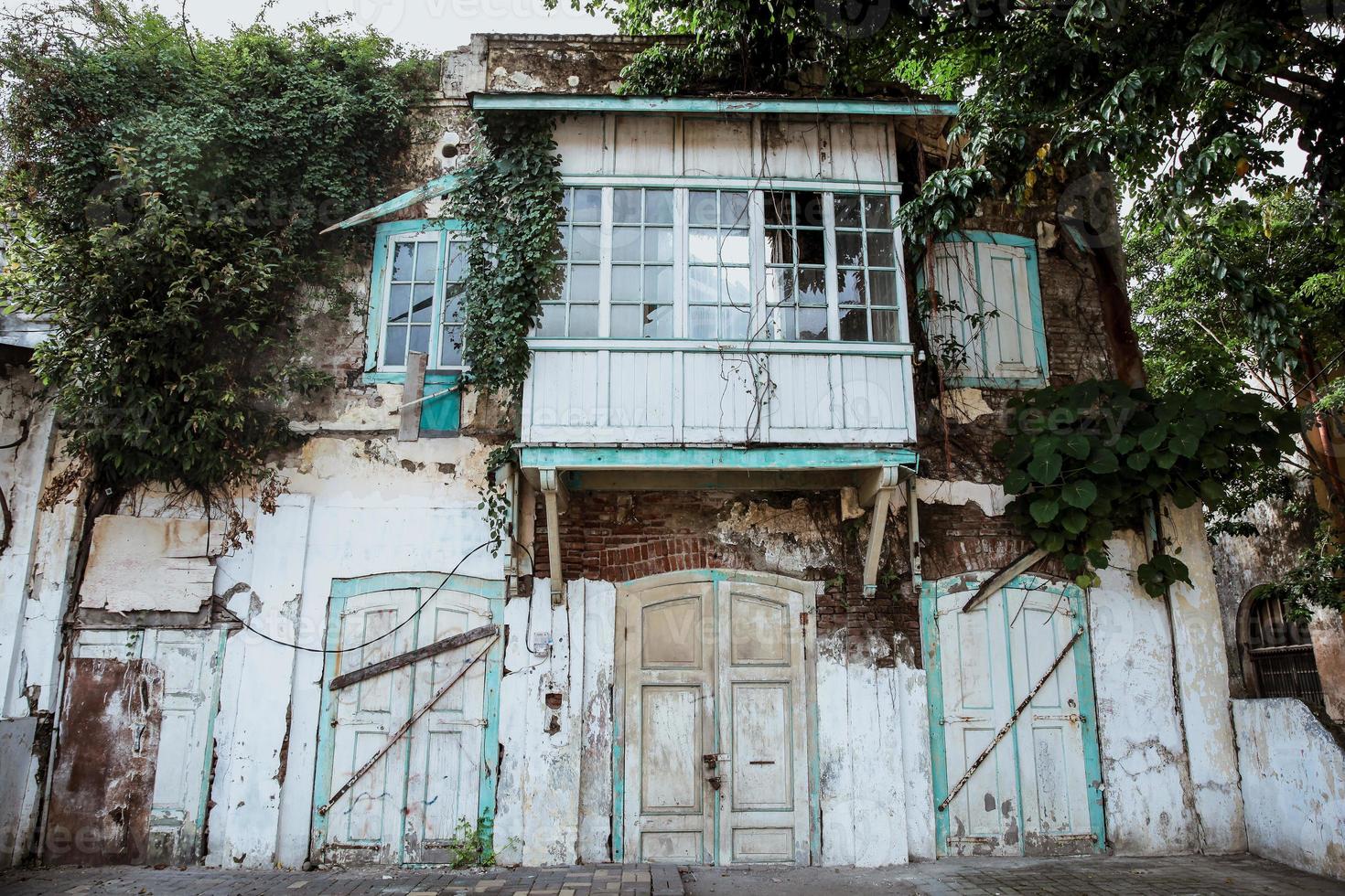 Messy facade of an old building with wild plant on wall and window photo