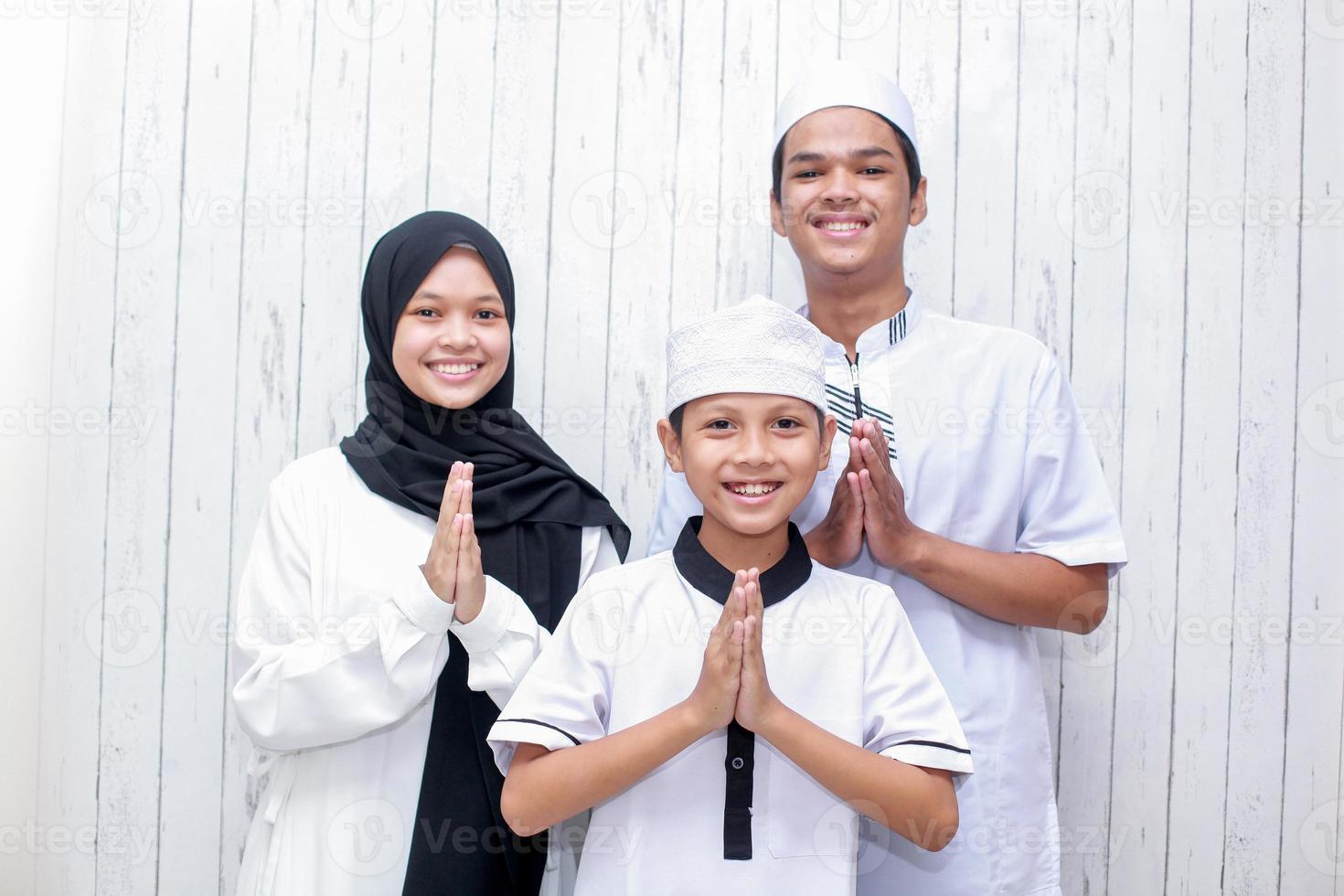 Young muslim family with hand greeting gesture for forgiveness on Eid Mubarak celebration photo