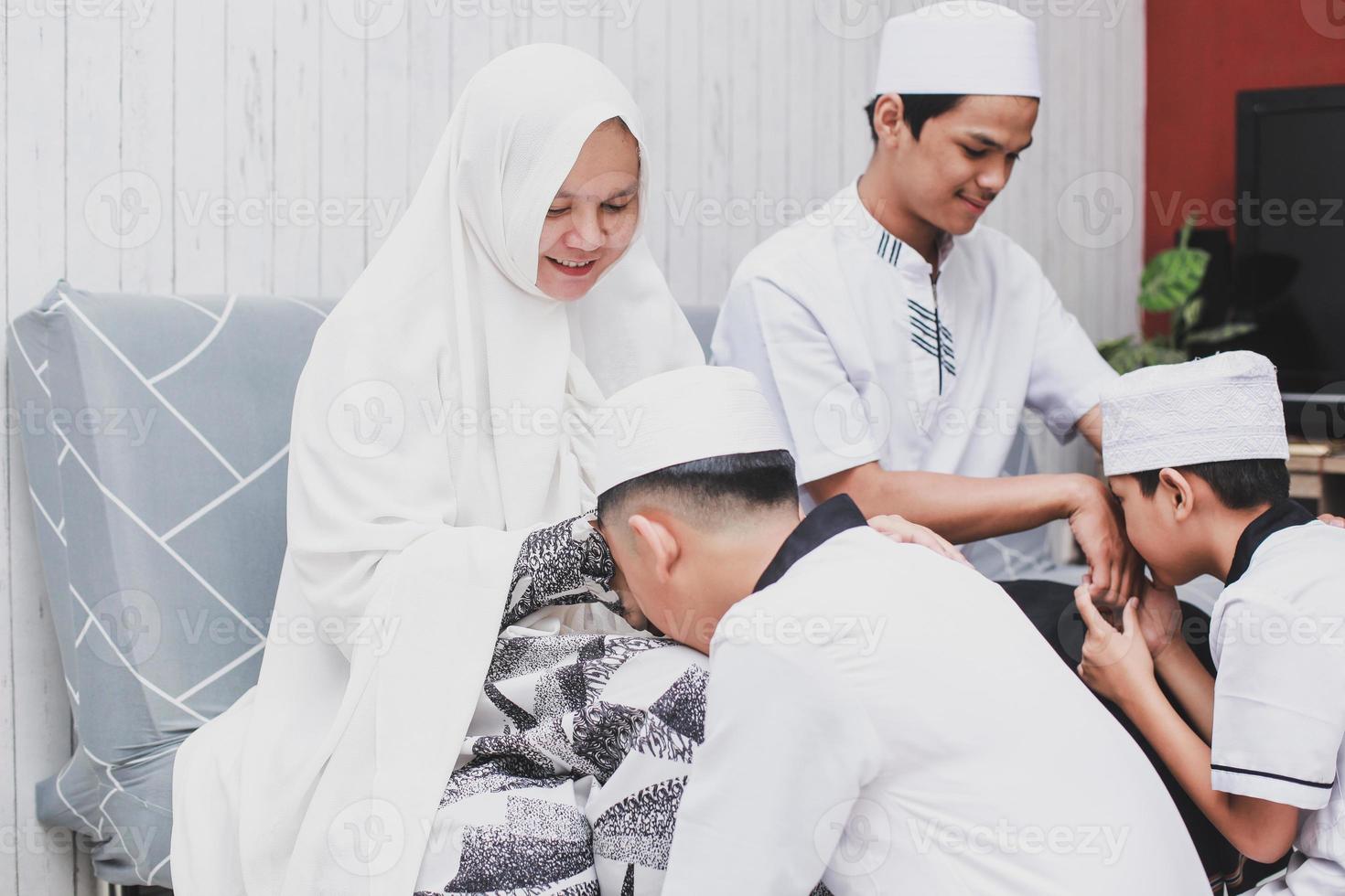 Asian family with traditional dress forgiving each other on Eid Mubarak celebration the kids kissing parents hand together photo