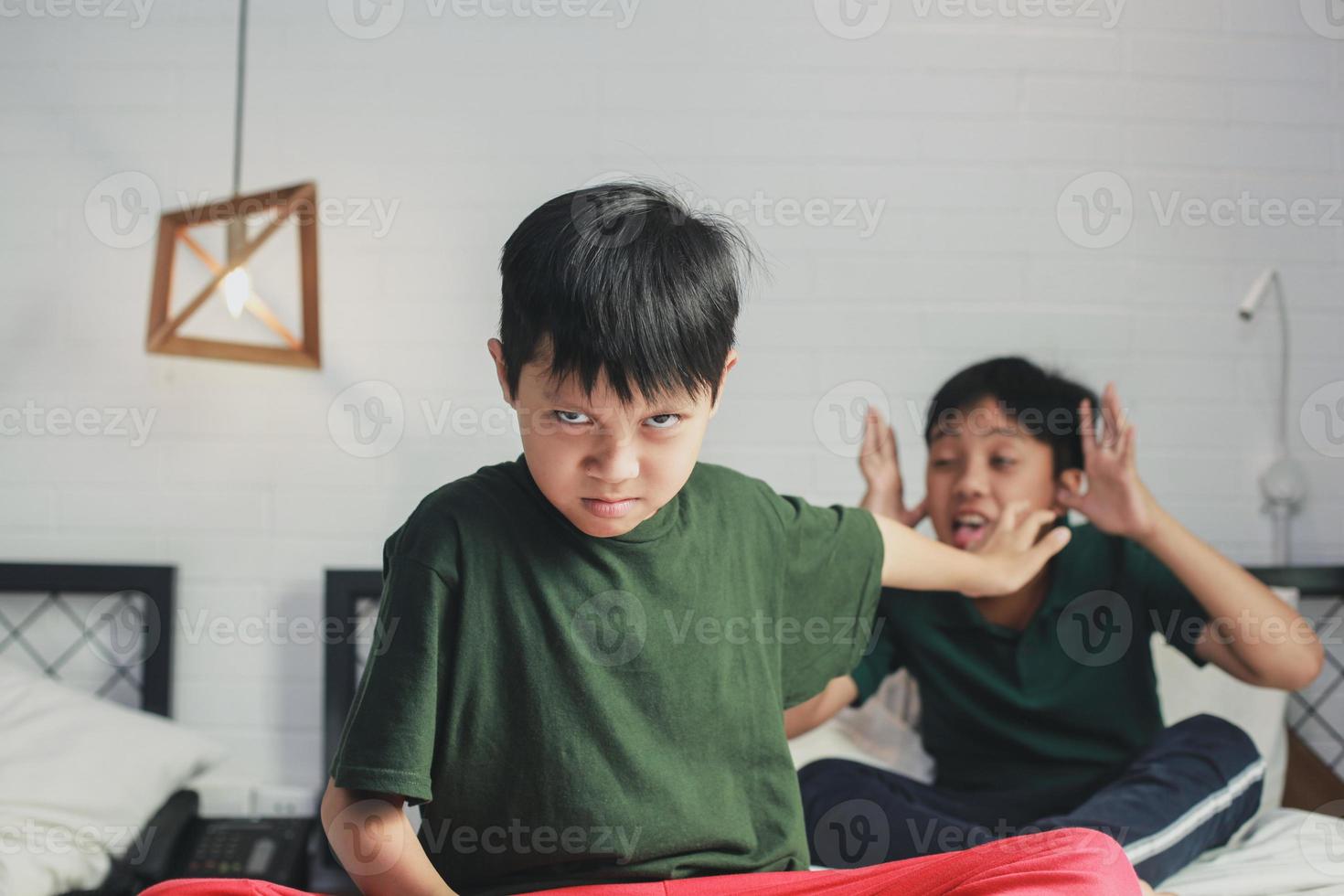 niño abusado por el hermano mayor haciendo un gesto de parada usando la mano en la cama foto