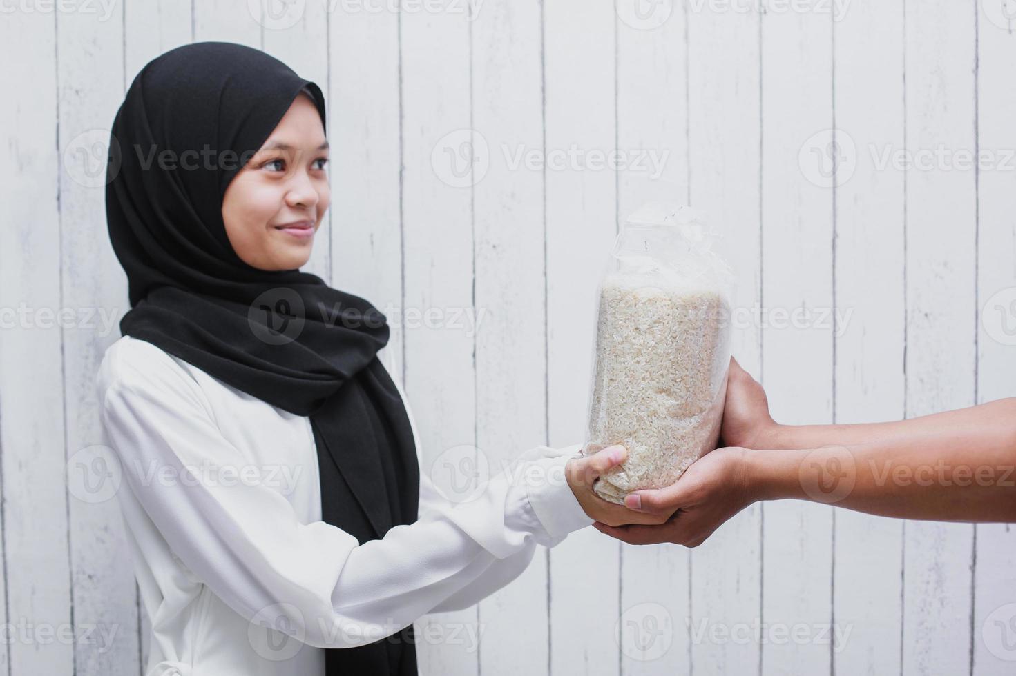 Young Muslim Woman giving rice for Zakat Fitrah as an obligation in the holy month of Ramadan photo