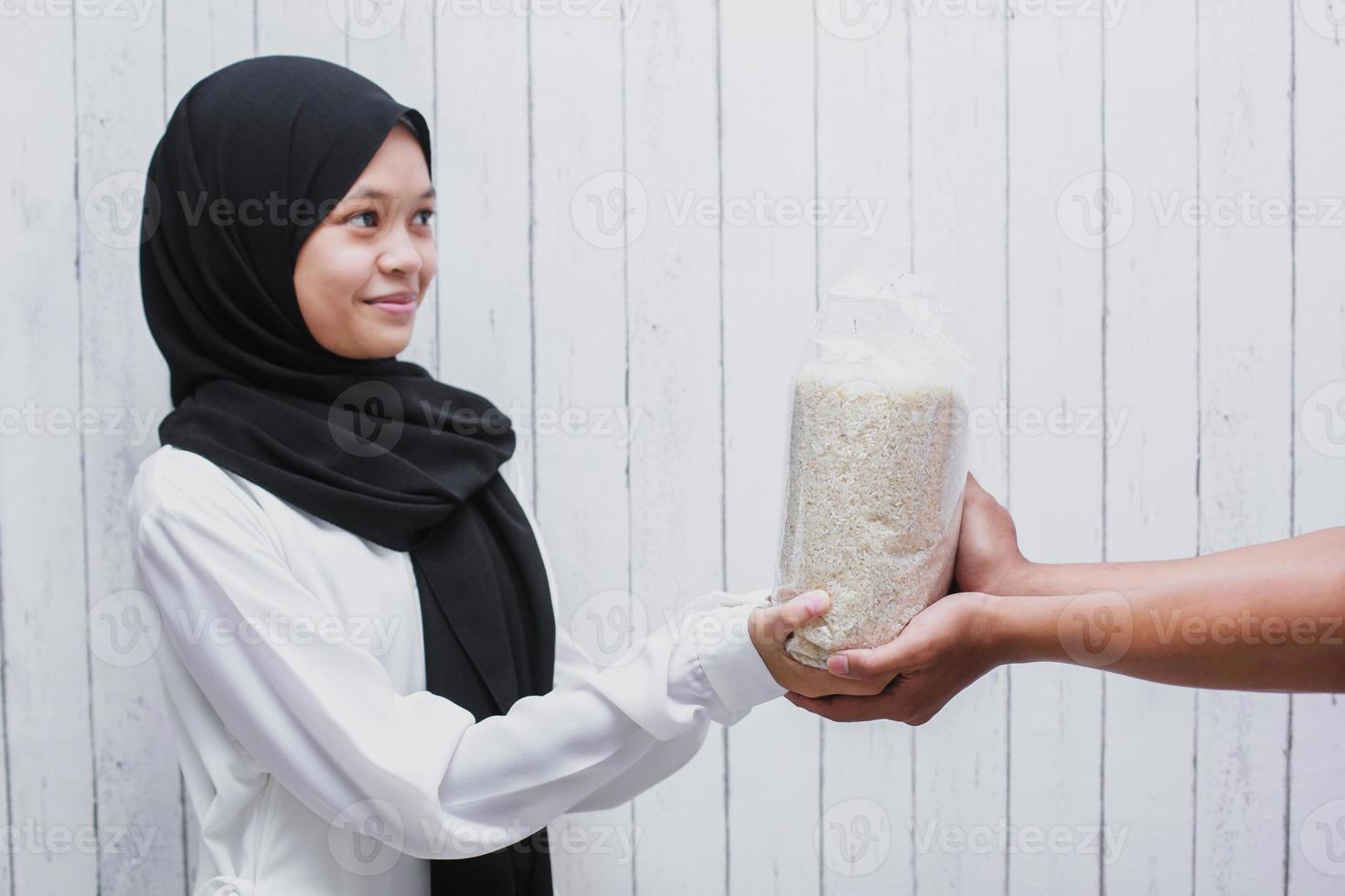 joven musulmana dando arroz para zakat fitrah como obligación en el mes sagrado del ramadán foto