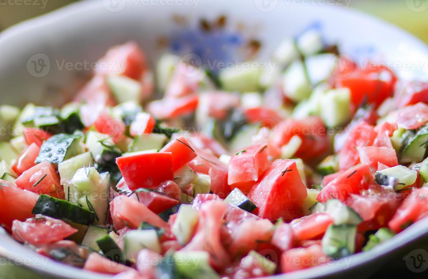 Fresh vegetable salad of tomatoes and cucumbers with sour cream and greenery photo