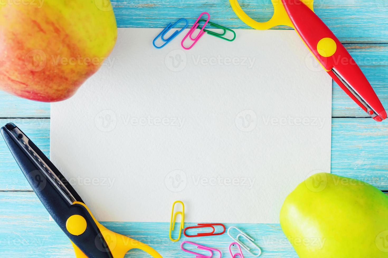 blank paper sheet, two apples and scissors on blue background, top view photo