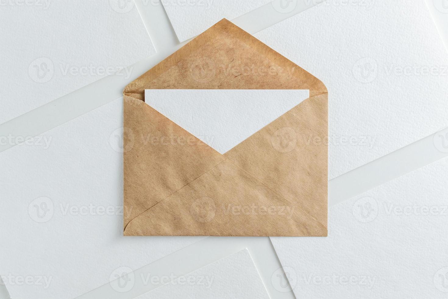 Blank white card in kraft brown envelope and paper sheets  template mock up photo