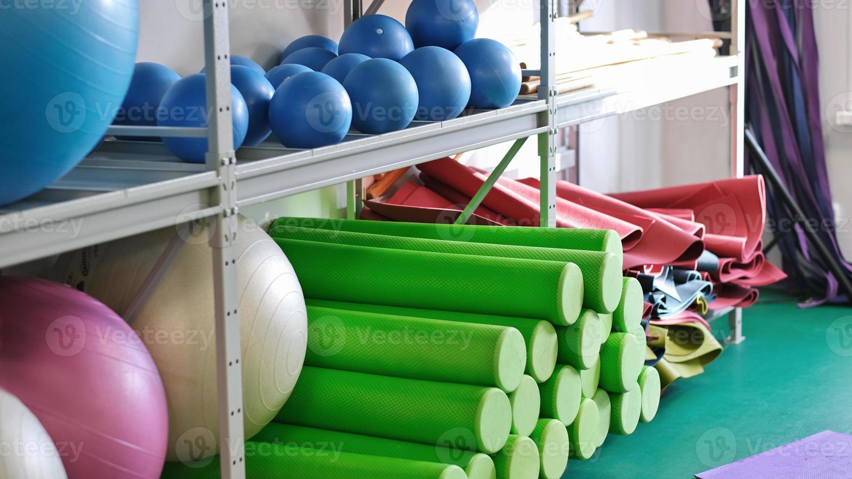 yoga and pilates equipment in a gym, fitballs, foam roller, mats for fitness and stretching practice, wellness and self care. sport club interior photo