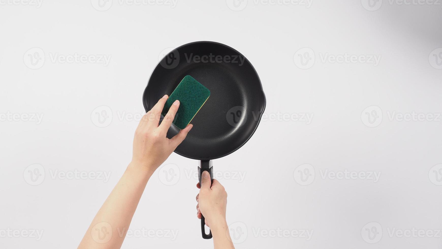 Hand cleaning the non stick pan with handy dish washing sponge photo