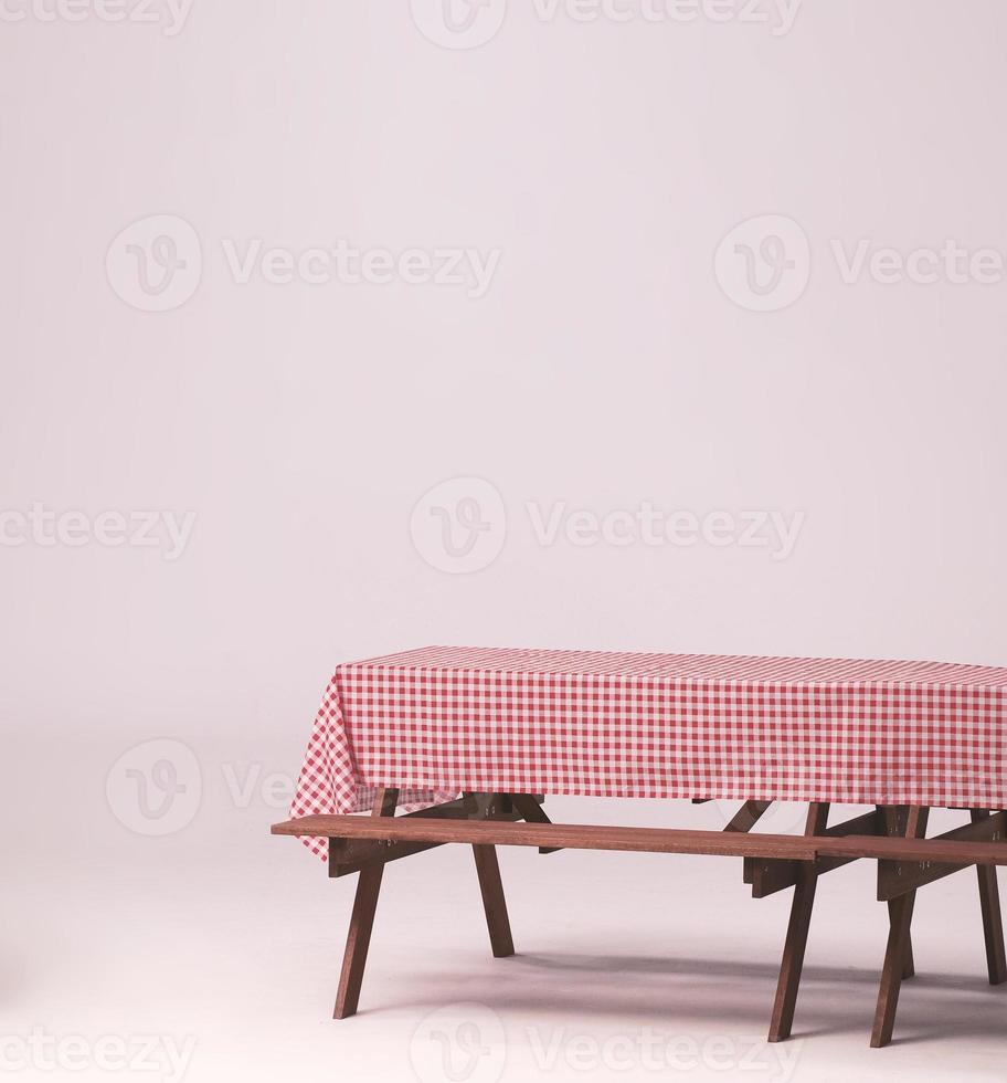 Picnic table and red checkered tablecloth with food and drink for outdoor party. Isolated photo