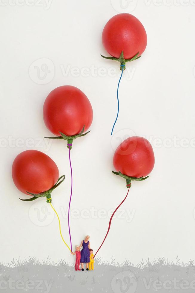 familia en miniatura jugando con globos de tomates cherry foto