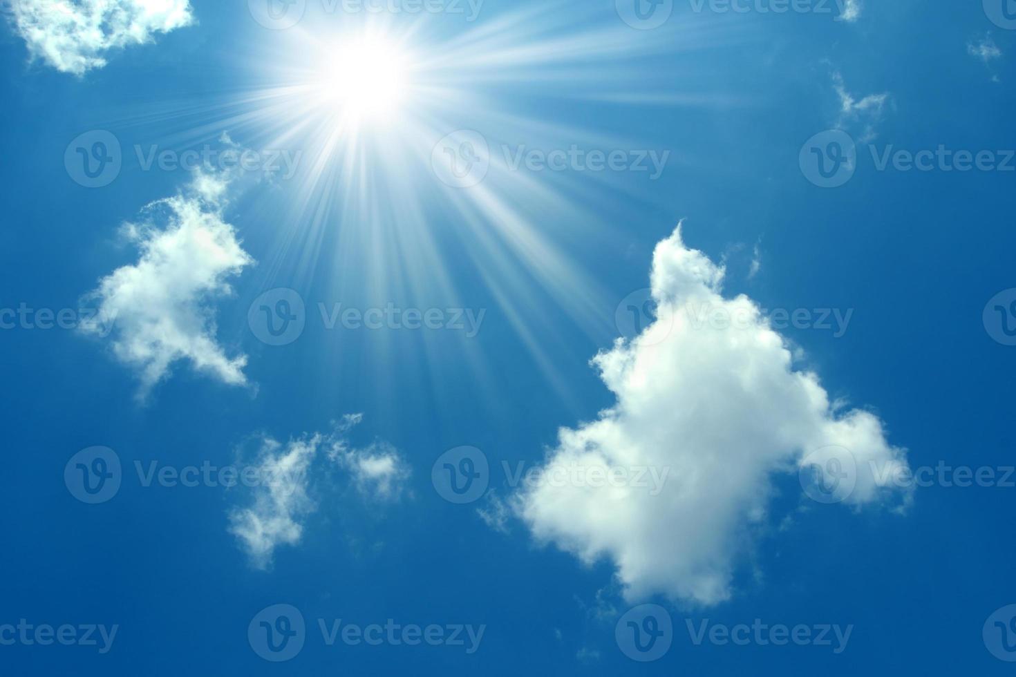 A blue sky with sun and clouds background. Shining sun on blue sky with clouds.Sunny sky background.Blue morning sky, bright sun rising and breaking through the white clouds.The bright midday sun photo