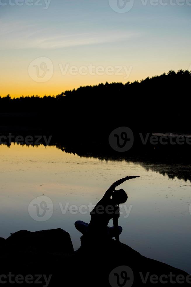 Silhouettes of a woman doing yoga at sunset photo