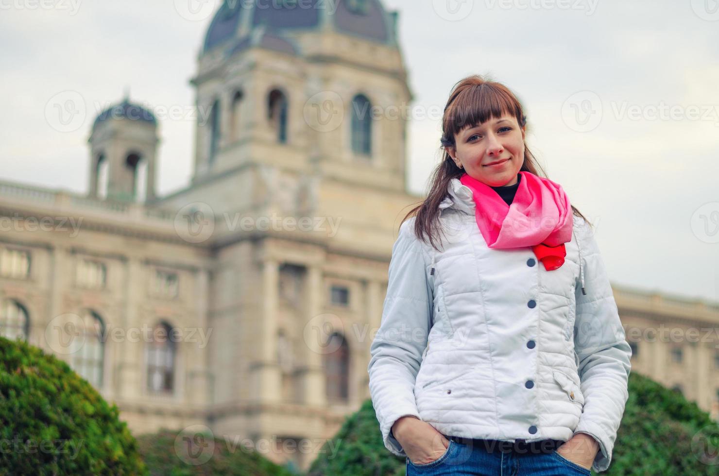 Young girl traveler with white jacket and red scarf looking at camera and posing, Kunsthistorisches Museum photo