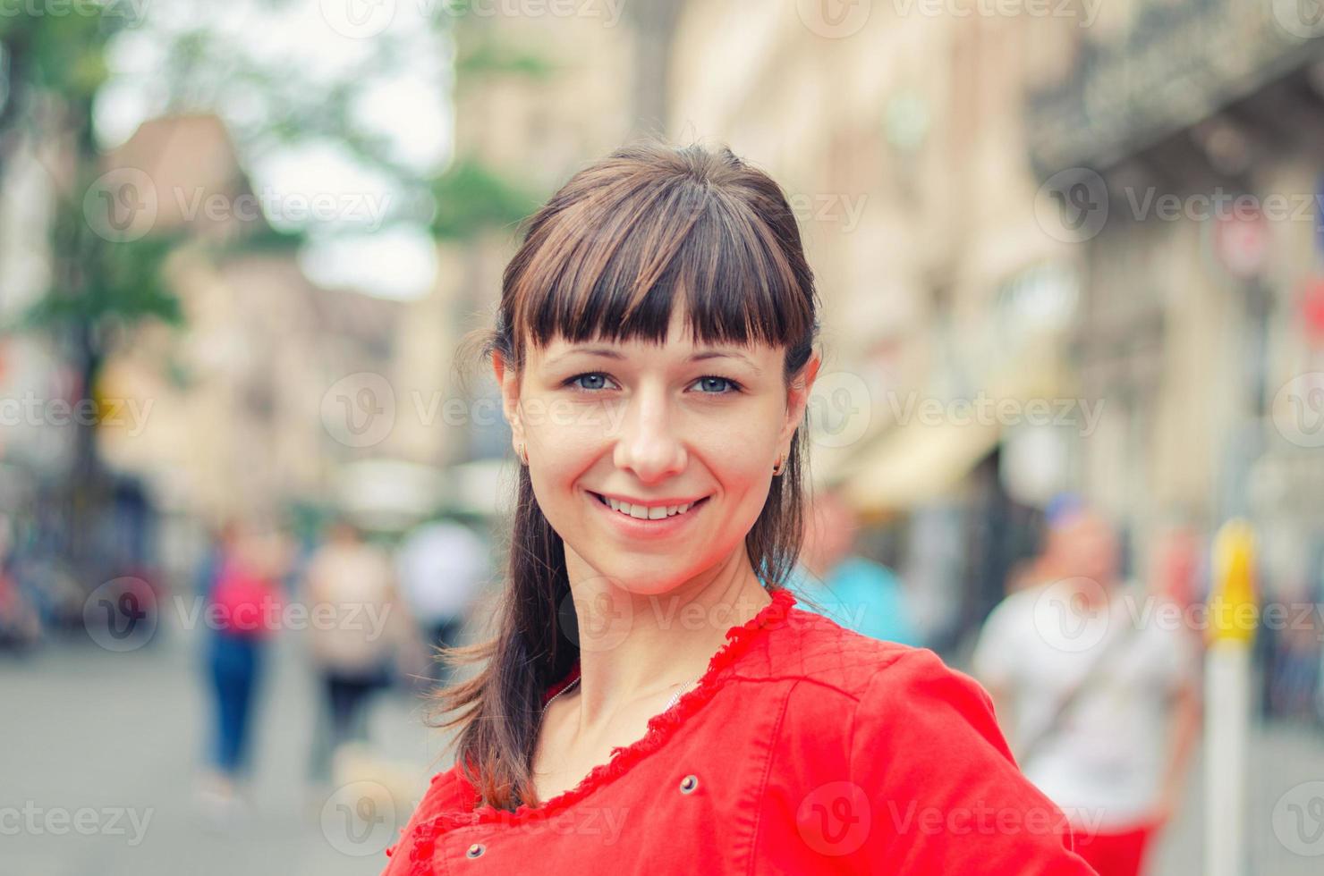 Close-up portrait of young beautiful caucasian girl with red jacket looking at camera and smile photo