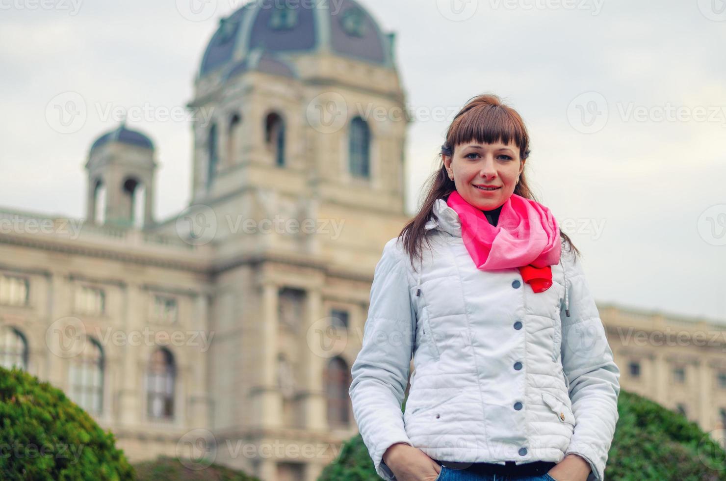 Young girl traveler with white jacket and red scarf looking at camera and posing, Kunsthistorisches Museum photo