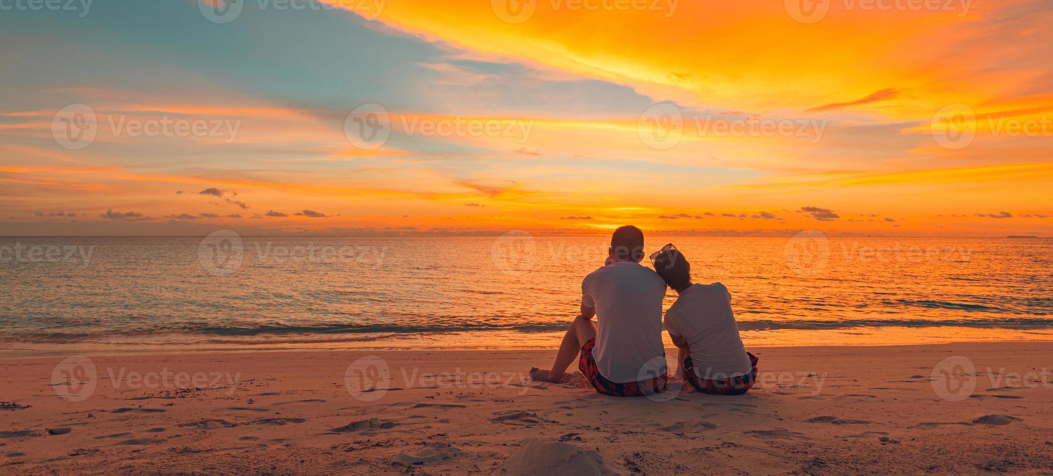 Romantic couple hugging on the beach on sunrise sunset. Honeymoon couple enjoying evening light relaxing on tropical summer vacation travel holiday. Two adults silhouettes lifestyle. photo