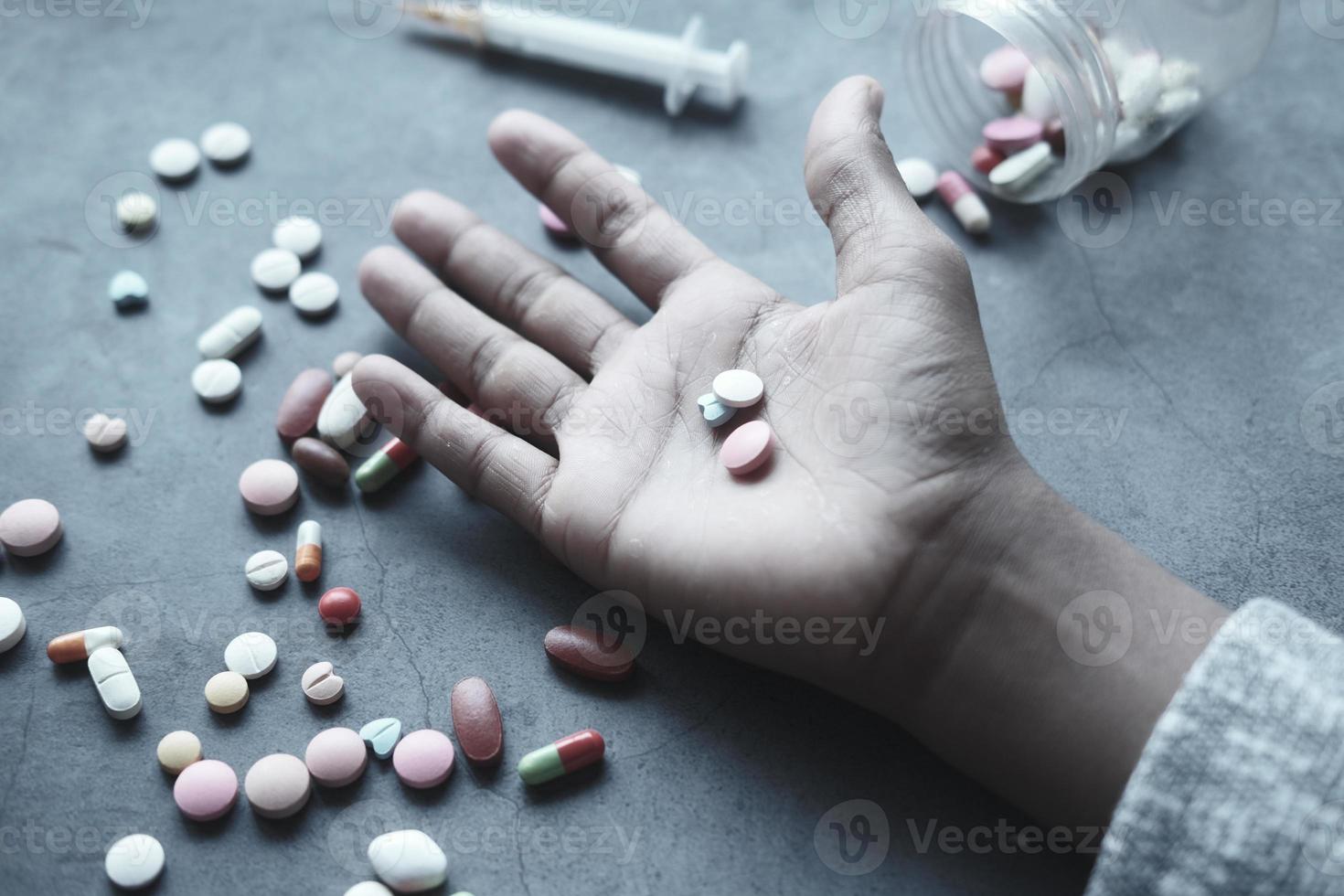 drug abuse concept with many pills on hand against black background photo