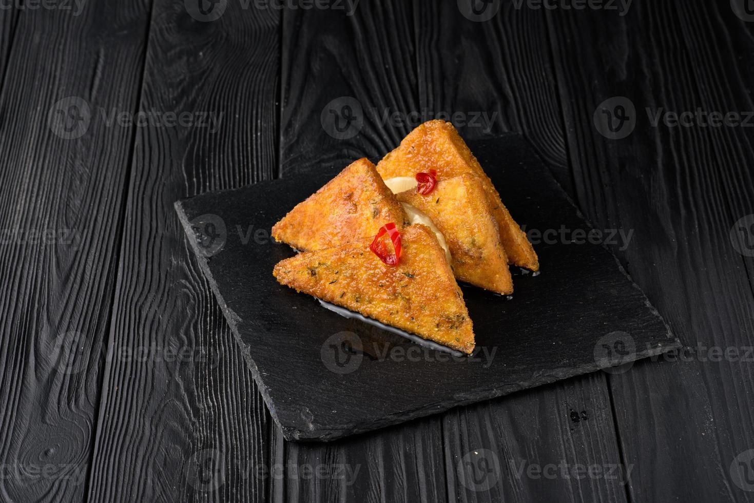 Fried tofu with pineapple on a black wooden background. photo