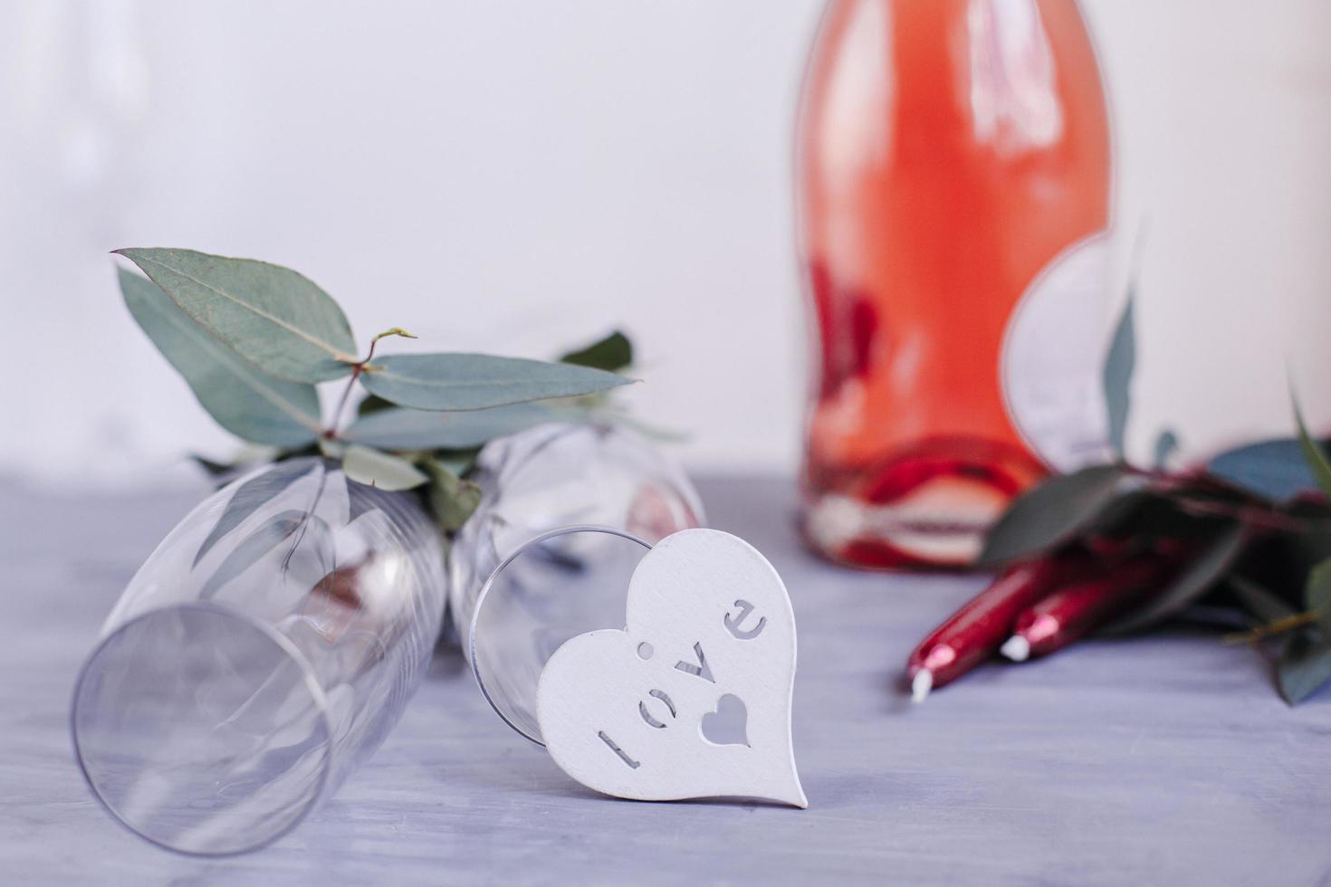 composición con botella de champán, velas y corazones para celebrar sobre fondo de hormigón gris. copa para champán. foto