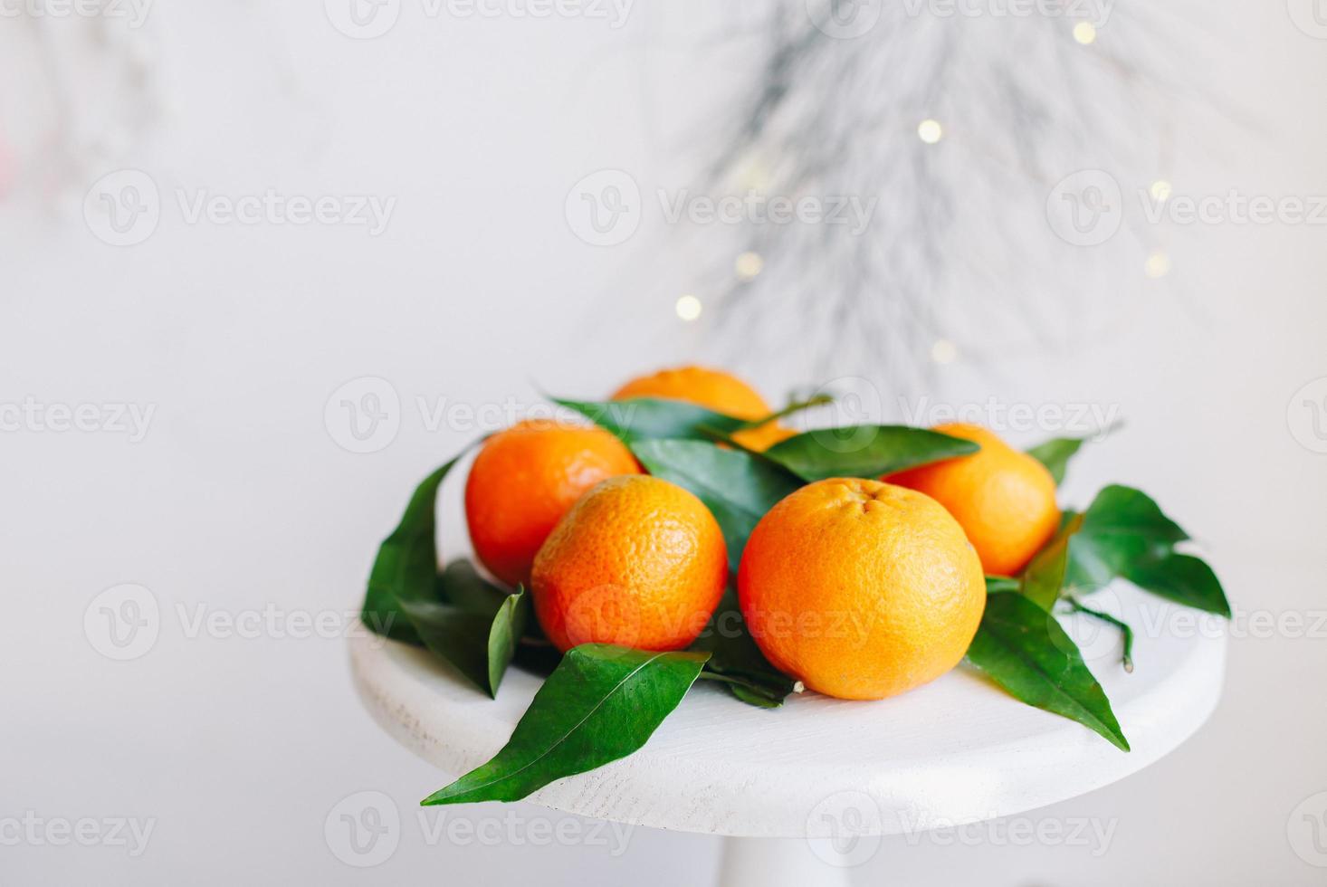 Orange tangerines on grey background in New Year's decor with brown pine cones and green leaves. Christmas decoration with mandarins. Delicious sweet clementine. photo