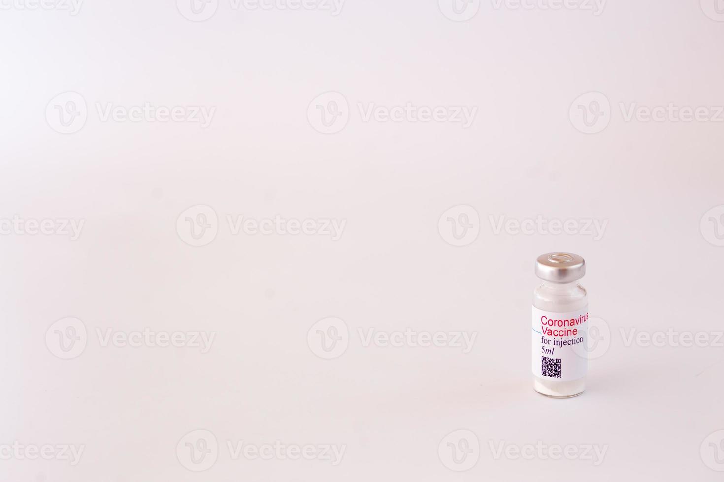 Coronavirus vaccine. Medical preparation in ampoule. Treatment for the disease, covid-19. The vaccine on a white background and on the background of a syringe, rubber gloves and goggles photo