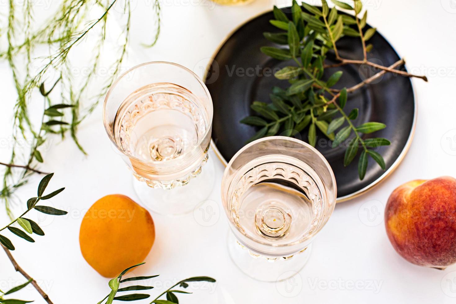 vino rosado en copas. vino rosado sobre fondo de botellas doradas con flores y frutas foto