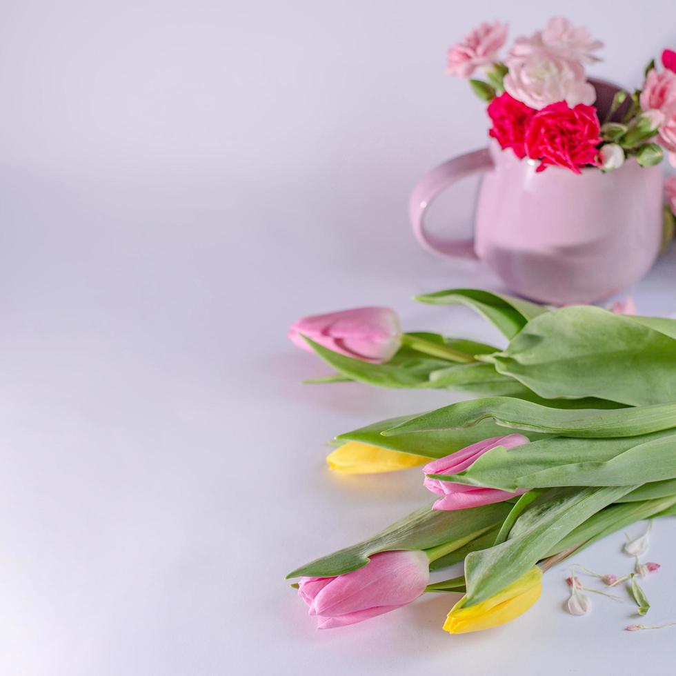 ramo de tulipanes amarillos y rosas sobre fondo blanco. taza con flores. fondo del día de san valentín y del día de la madre. foto