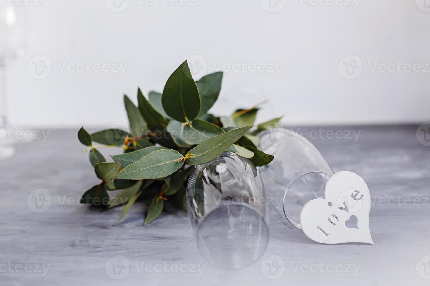 composición con copa para champán. flores y corazones sobre fondo de hormigón gris. foto