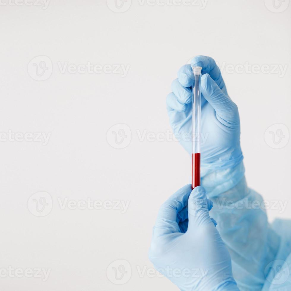 Close up copy space of doctor hand with blood sample. Blood test. A doctor wearing personal protective equipment including mask, goggle, and suit to protect COVID-19 coronavirus infection. photo