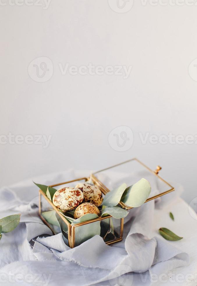 composición de pascua. huevos de pascua en una caja de vidrio sobre cintas de seda y sobre fondo blanco y gris. copie el espacio foto