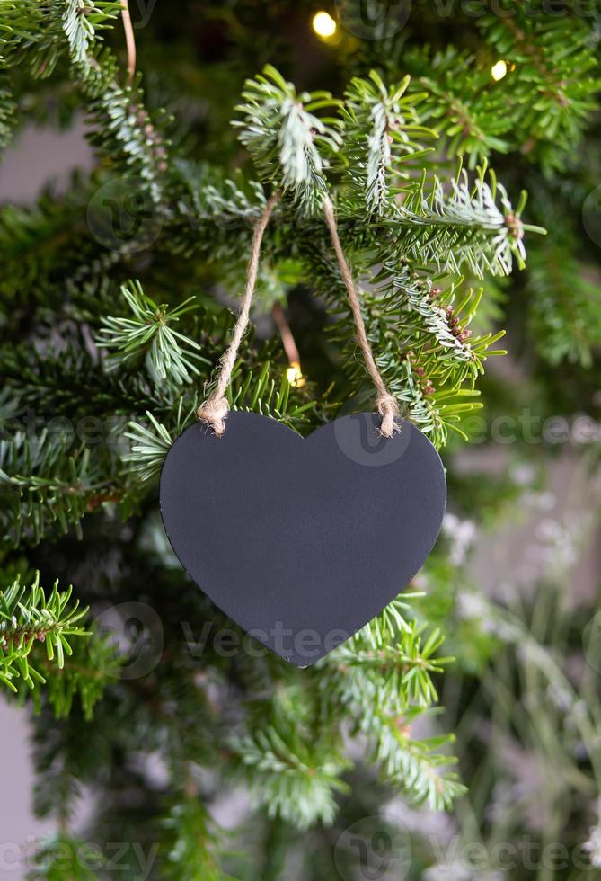 Black wooden heart on a background of fir branches. Christmas New Year composition. Moke up, copy space for Valentine's Day. photo