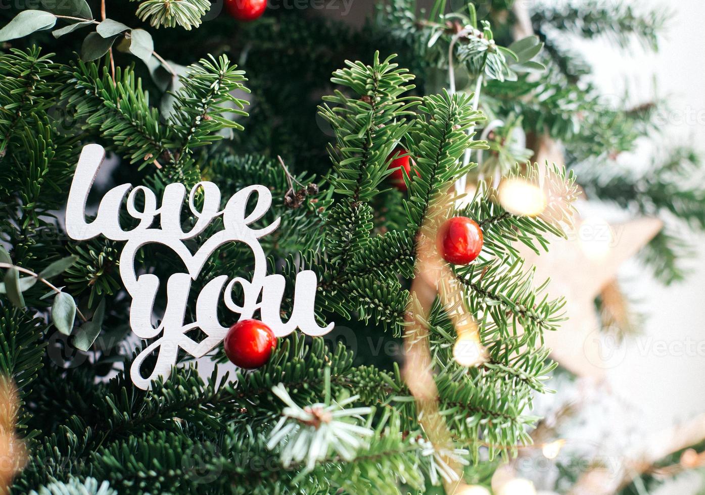 Love you wooden inscription on green fir background. White wooden phrase for valentine's day. photo