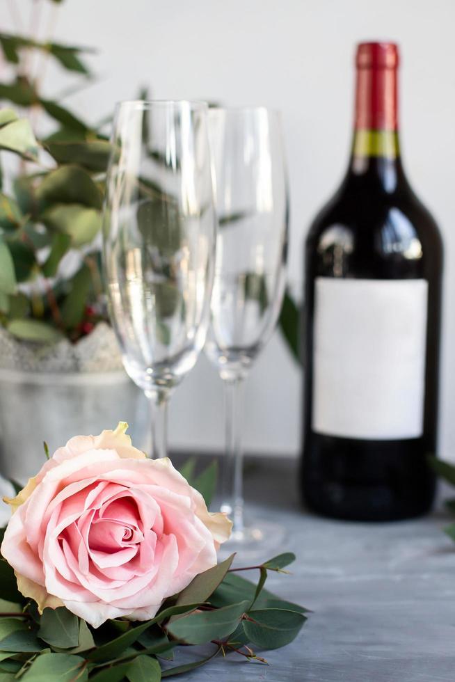 Composition with glass, flowers and bottle of vine on grey concrete background. photo