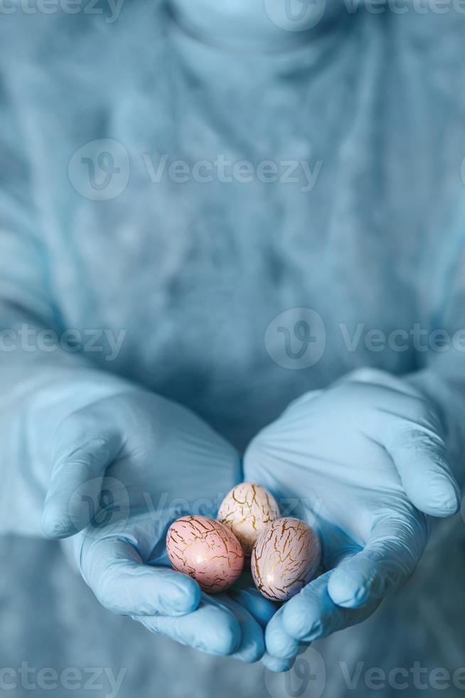 Hands in medical gloves holding modern painted easter eggs. Selective focus. Toned picture. photo