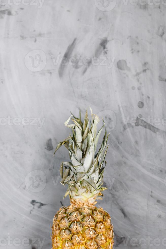 White Plate with Ripe Whole Pineapple on Grey Concrete Background. Copyspace photo