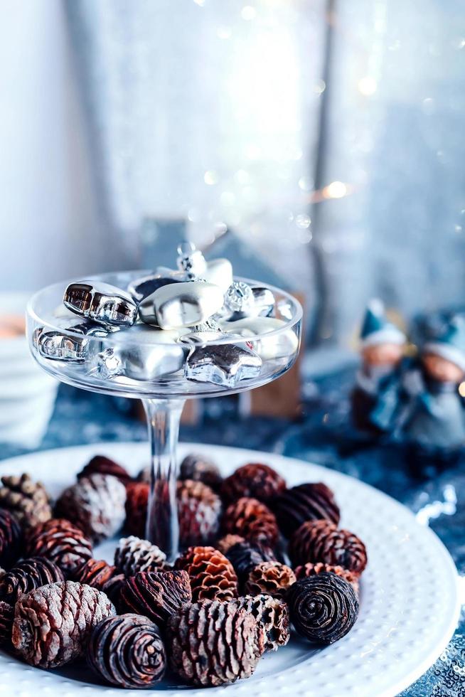 Glass silver stars in a glass vase. Christmas tree toys in a glass on a background of shiny fabric and fir cones. Copy space. photo