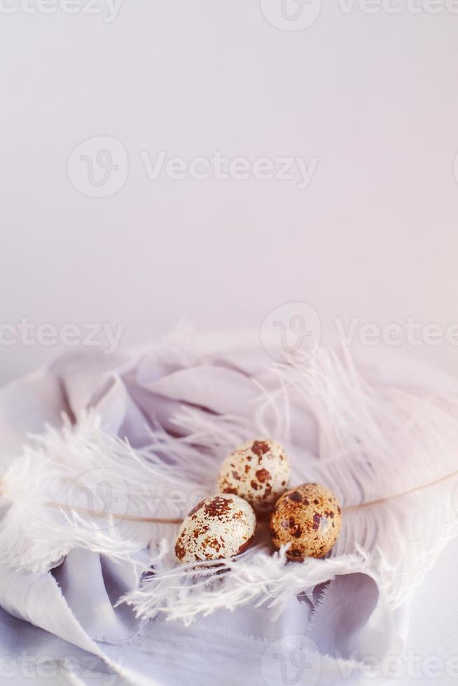 huevos de pascua con pluma blanca sobre fondo blanco y gris. felices vacaciones de pascua, vista frontal superior. foto