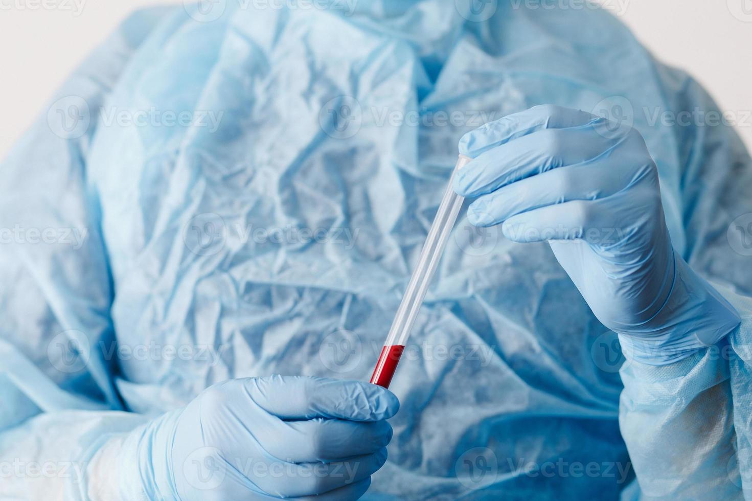 Close up of doctor hand holding blood sample. Medical equipment. Blood test. A doctor wearing personal protective equipment including mask, goggle, and suit to protect COVID-19 coronavirus infection. photo