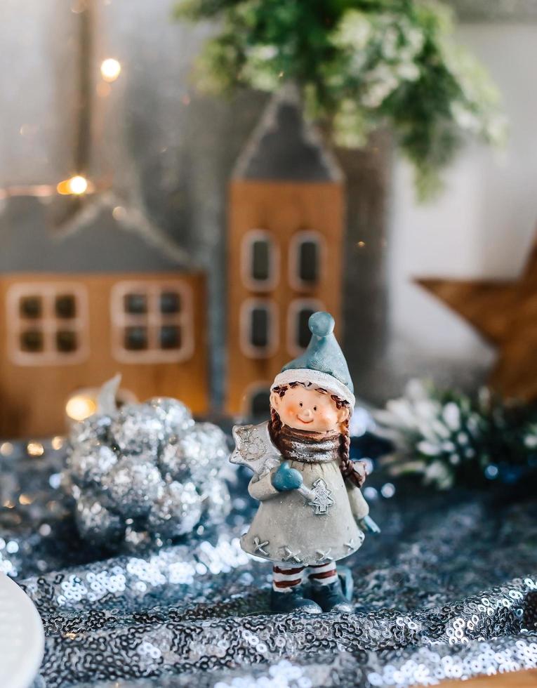 Porcelain figurines of children in a Christmas decor. Winter figurines of a boy and a girl with gifts on the background of houses and cones. Christmas Greeting Card. Copy space. photo