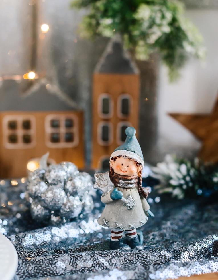 figuritas de porcelana de niños en una decoración navideña. figuras de invierno de un niño y una niña con regalos en el fondo de casas y conos. tarjeta de felicitación de navidad. copie el espacio foto