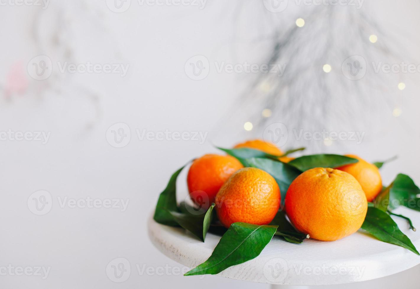 Orange tangerines on grey background in New Year's decor with brown pine cones and green leaves. Christmas decoration with mandarins. Delicious sweet clementine. photo