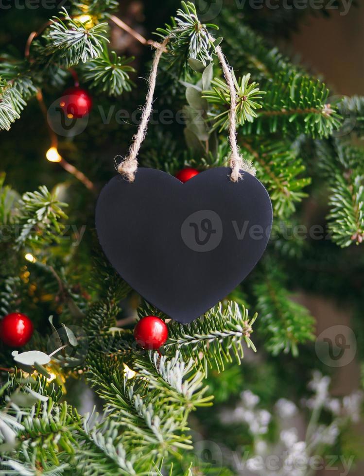Black wooden heart on a background of fir branches. Christmas New Year composition. Moke up, copy space for Valentine's Day. photo