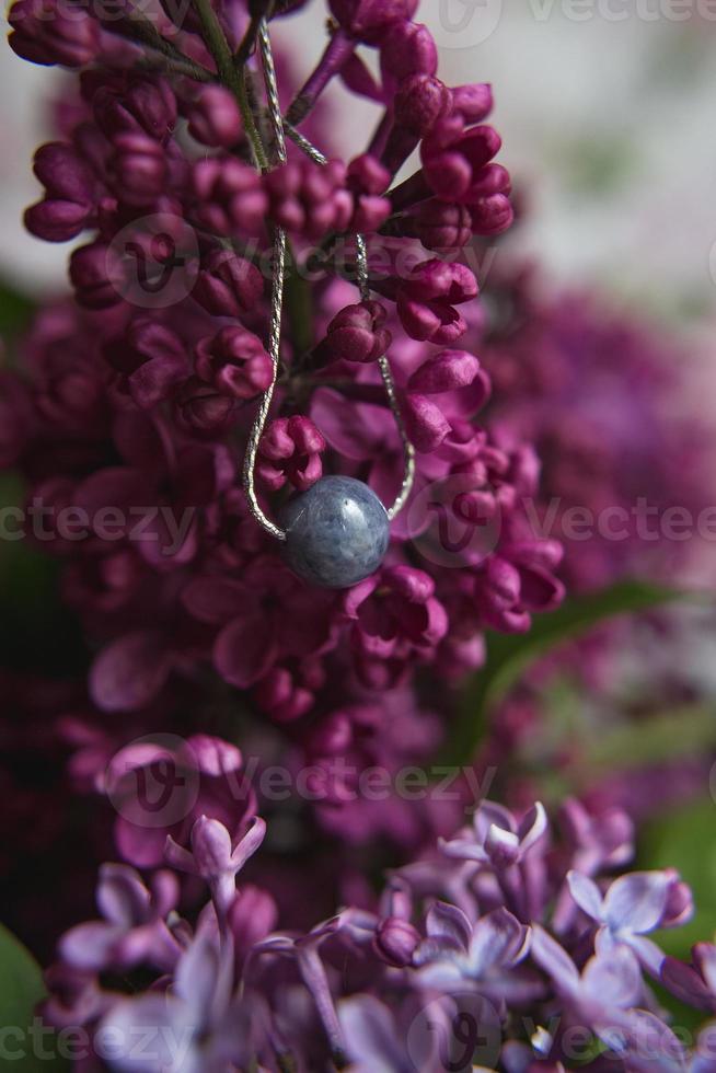 collar de piedra natural con fornitura de plata con flores lila violeta violeta sobre pluma de avestruz blanca. accesorios de plata foto