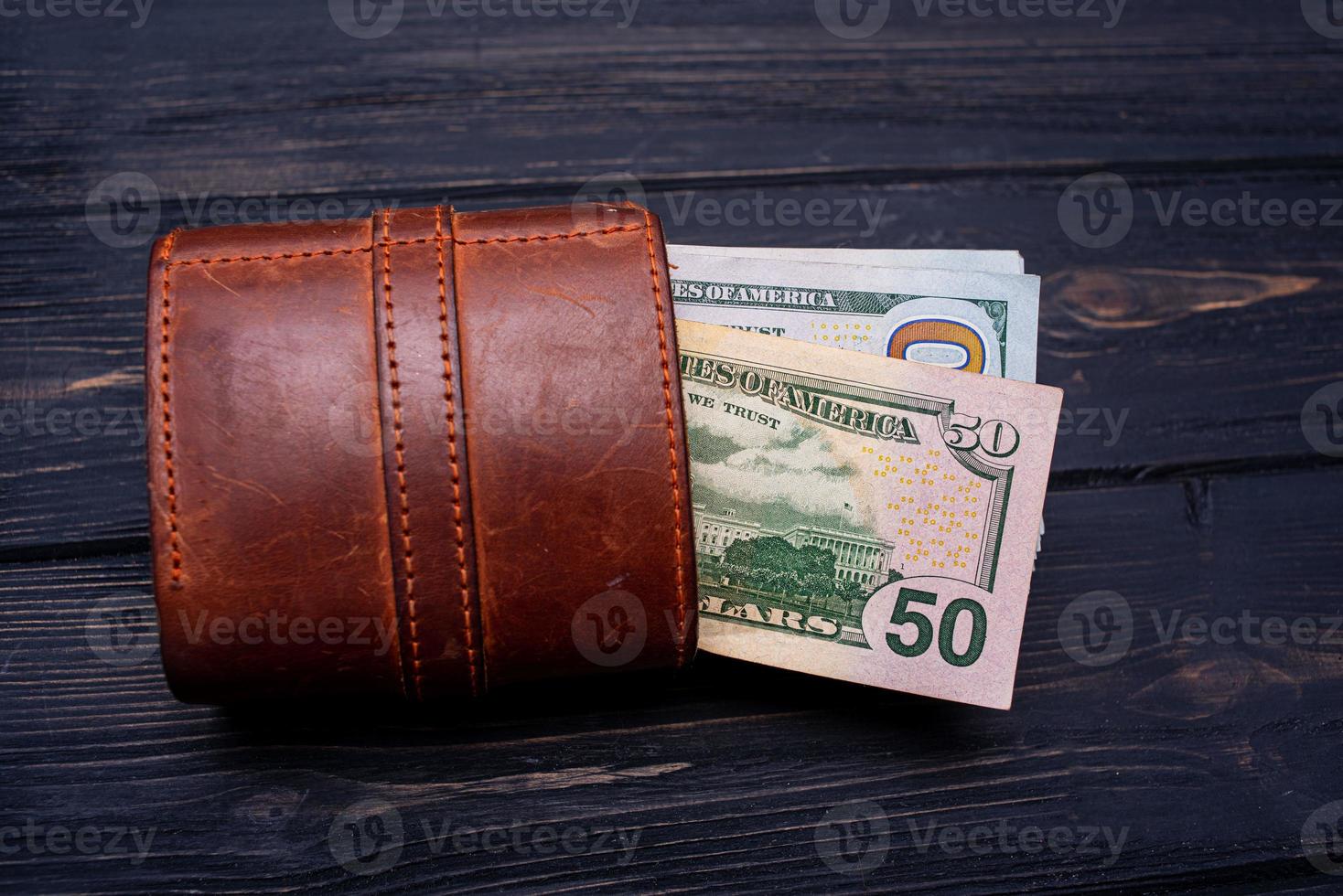 Dollars in a brown wallet on a black cement background. Financial and business concept. photo