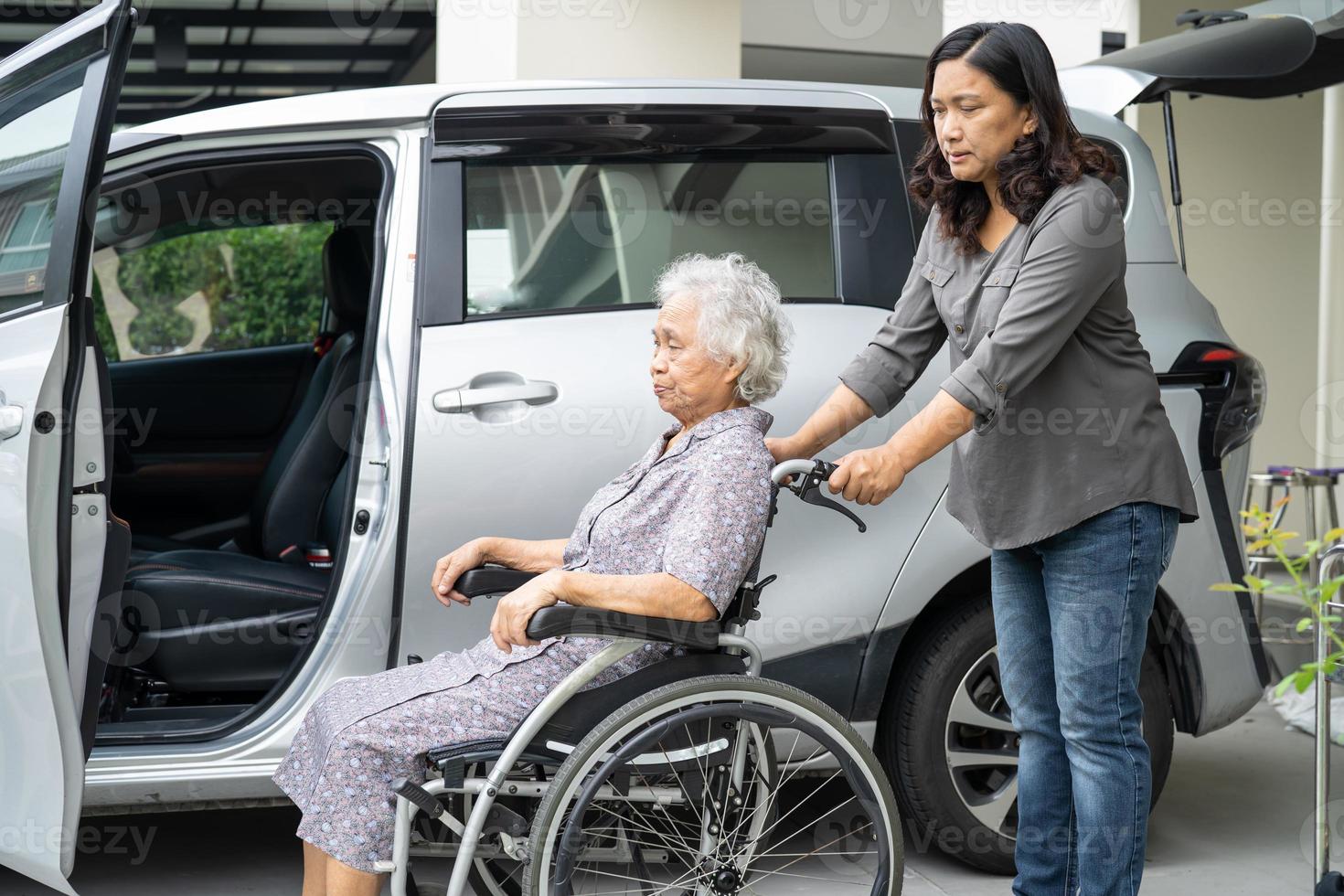 Help and support asian senior or elderly old lady woman patient sitting on wheelchair prepare get to her car, healthy strong medical concept. photo