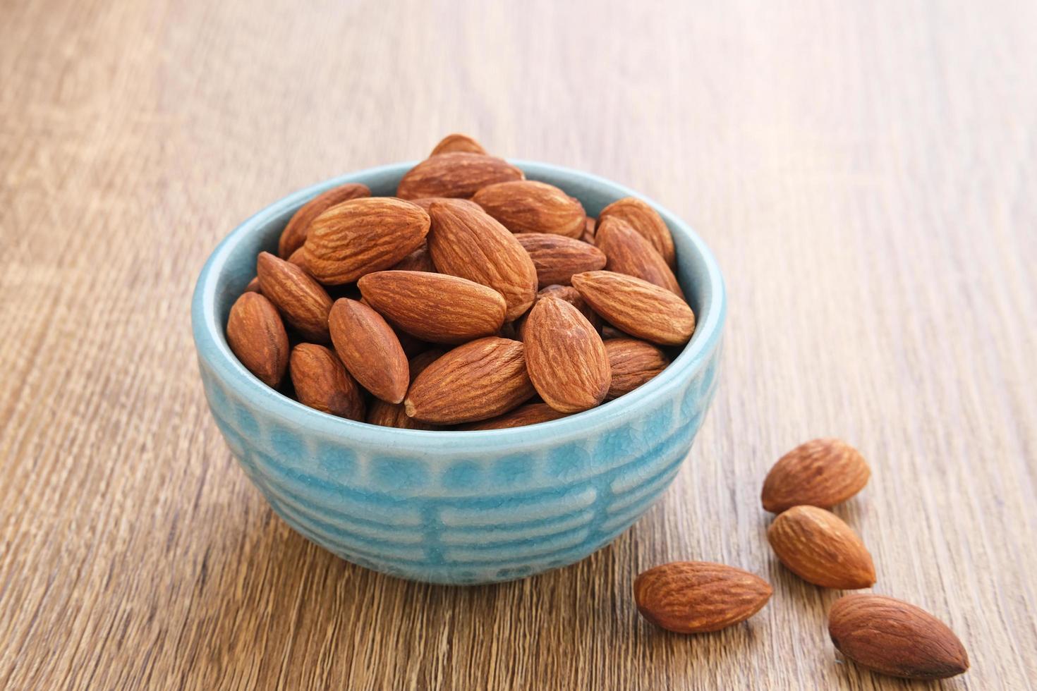 Almonds in bowl on wooden table.  Close up. Selected focus photo